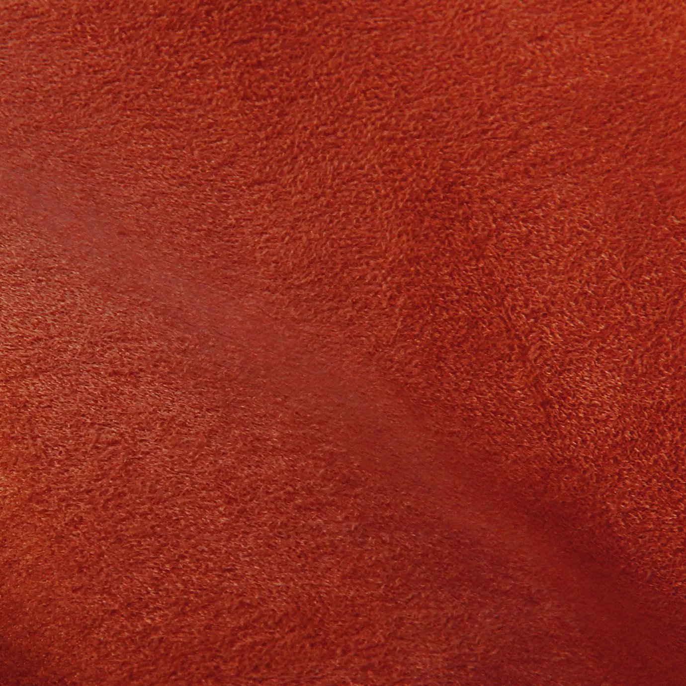 Soft close-up of an Ultra Suede Grenadine fabric swatch in a vibrant and warm reddish-orange tone, showcasing its delicate texture and a gentle touch that gives it a feeling of comfort and natural elegance.