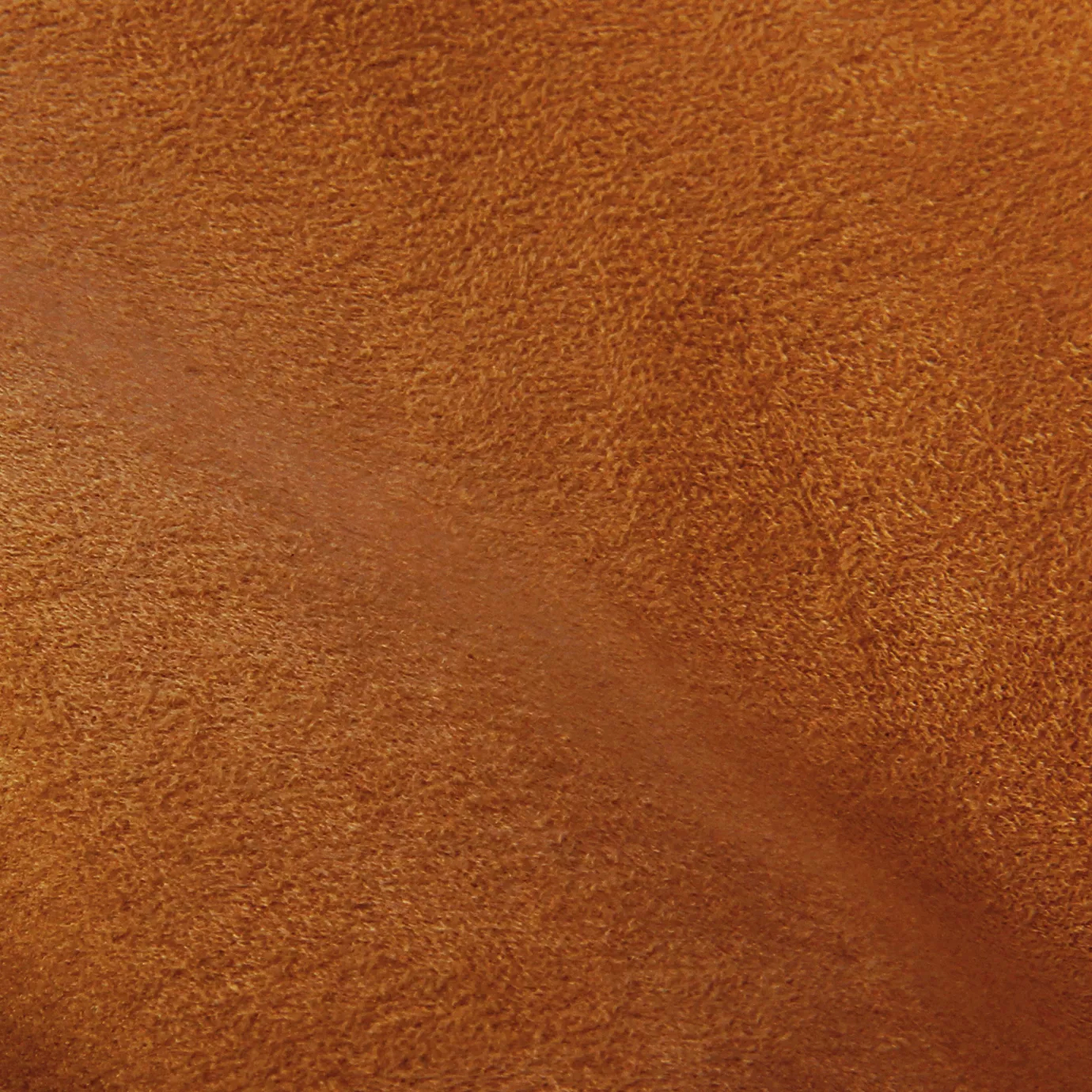 Soft close-up of an Ultra Suede Pumpkin fabric swatch in a warm and vibrant pumpkin orange tone, showcasing its delicate texture and a gentle touch that gives it a feeling of comfort and natural elegance.
