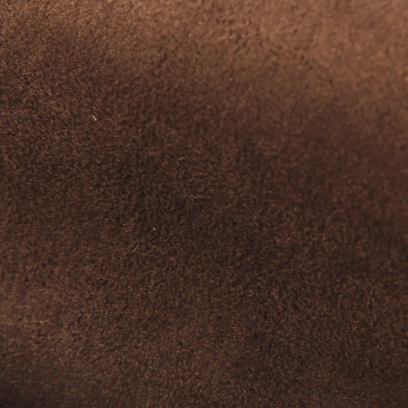 Soft close-up of an Ultra Suede Root Beer fabric swatch in a warm and rich root beer brown tone, showcasing its delicate texture and a gentle touch that gives it a feeling of comfort and natural elegance.