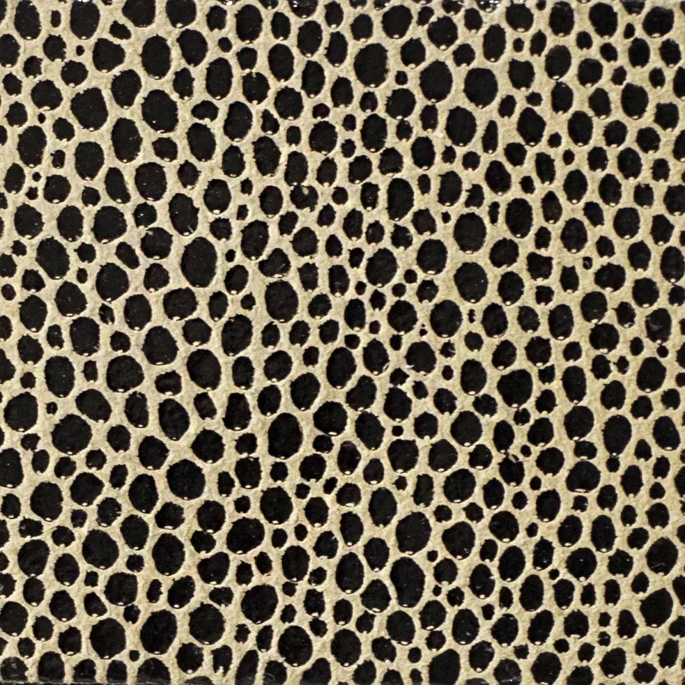 Elegant close-up of a Crico Black leather swatch with a textured pattern of small black dots on a light beige base, featuring a smooth surface with a striking contrast, evoking a feeling of modern elegance and a touch of graphic sophistication.