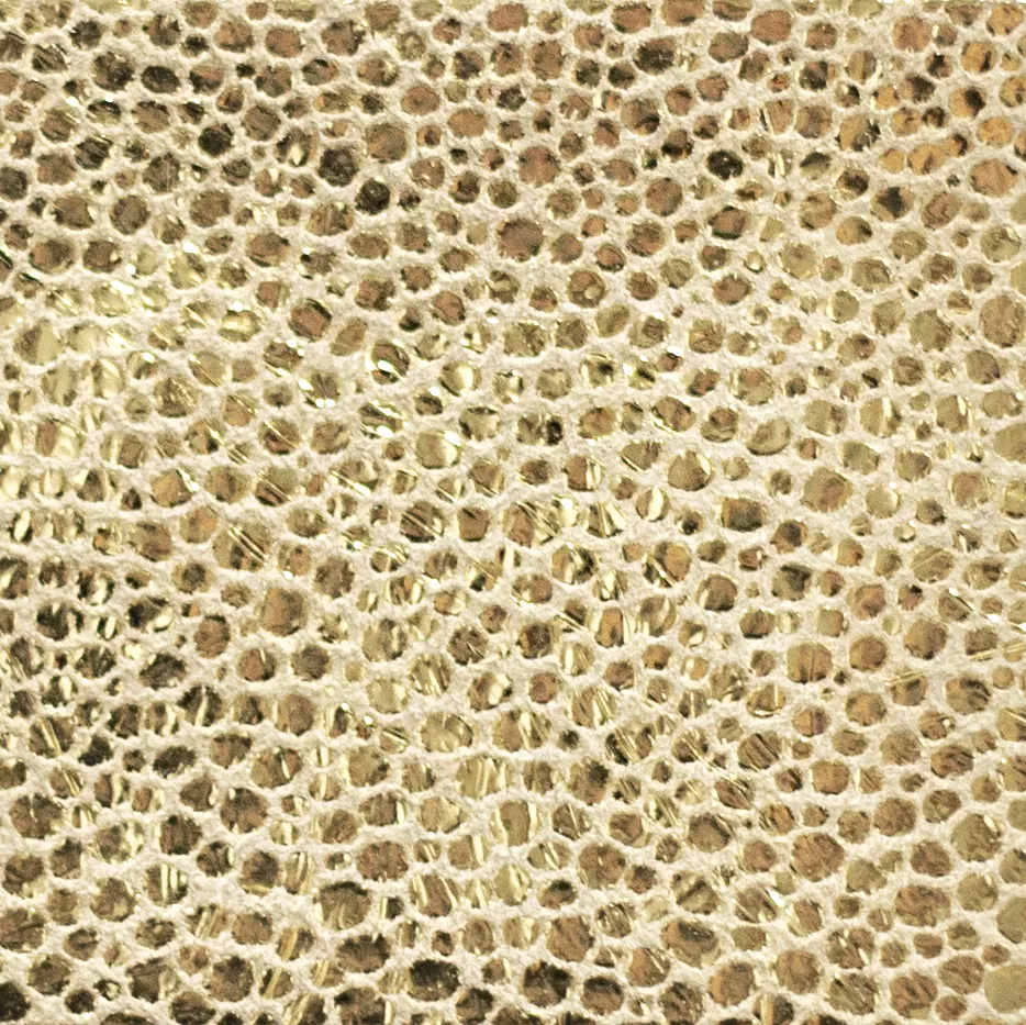Elegant close-up of a Crico Gold leather swatch with a textured pattern of small gold dots on a light beige base, featuring a smooth surface with a luxurious sheen, evoking a feeling of modern opulence and a touch of radiant elegance.