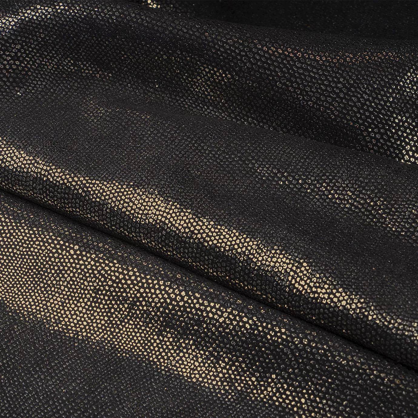 Close-up Pixel Gold Leather: textured black leather with small, shiny golden dots. Features soft folds and light reflections.