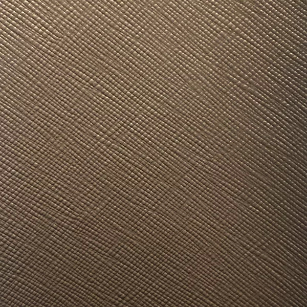 A detailed view of Nomad Synthetic Leather in a warm brown shows a fine, diagonal cross-hatch texture with subtle variations.