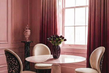 Round marble dining table with sculptural chairs in a cinematic, blush-toned interior by KOKET