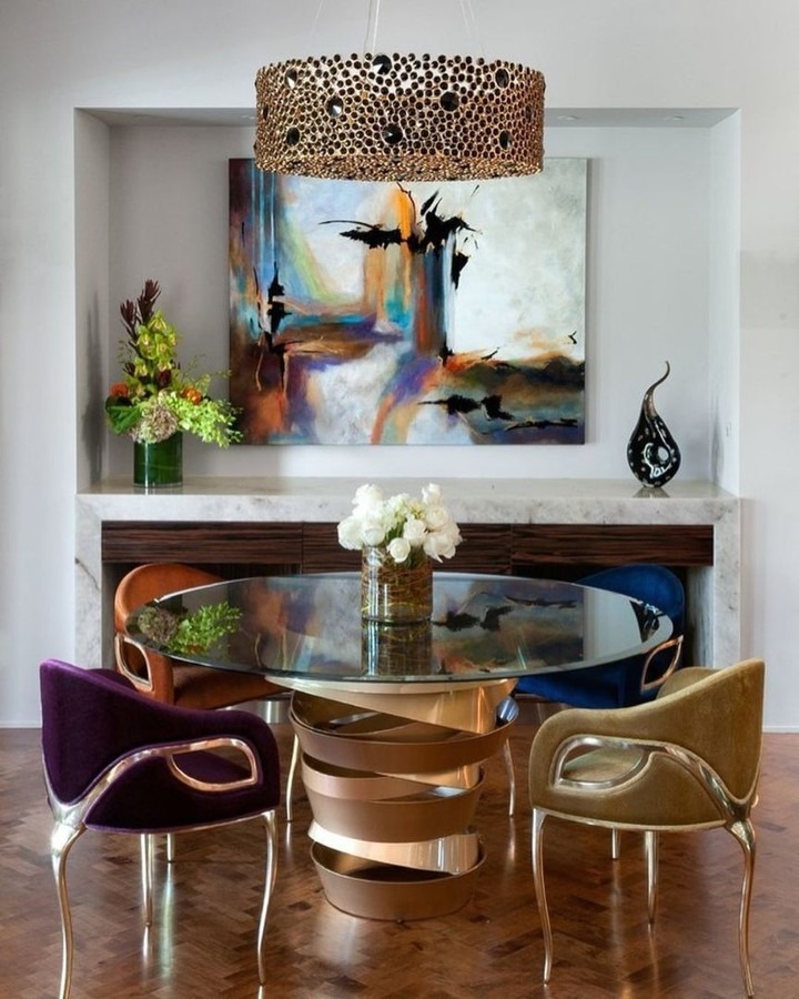 Four Chandra Chairs in different colorways — purple, rust, blue, and gold — around a glass dining table - design by Beverly Hills Luxury Interiors