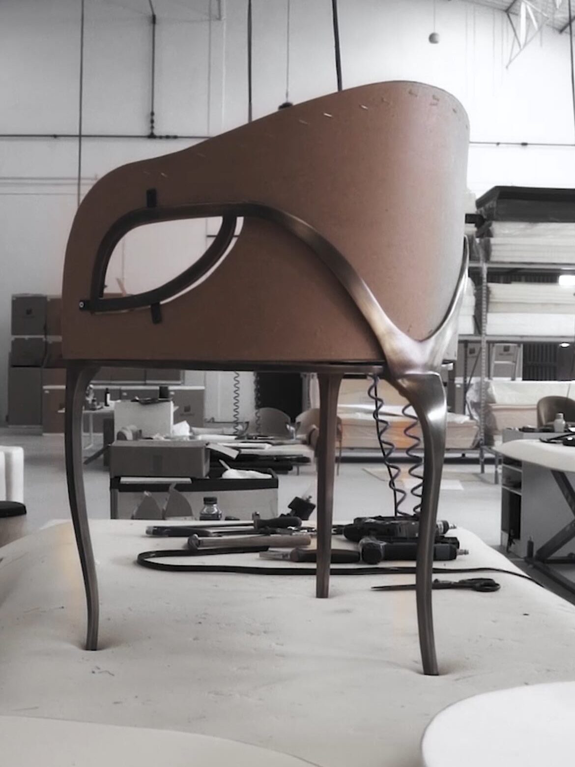 Raw Chandra Chair frame on the workshop floor surrounded by artisan tools