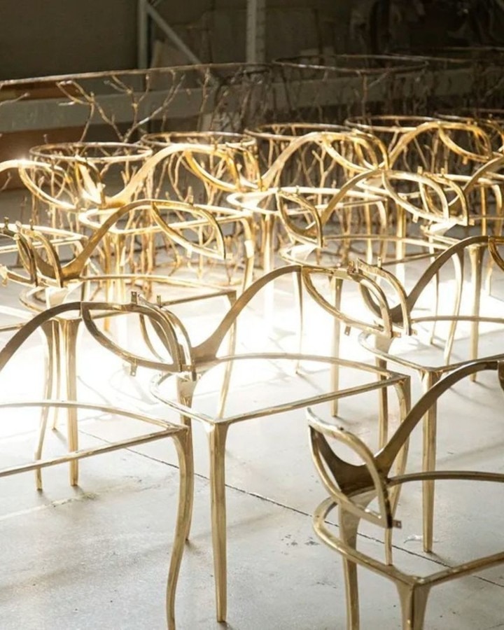 Rows of bare brass Chandra Chair frames glowing under workshop lights in the KOKET atelier