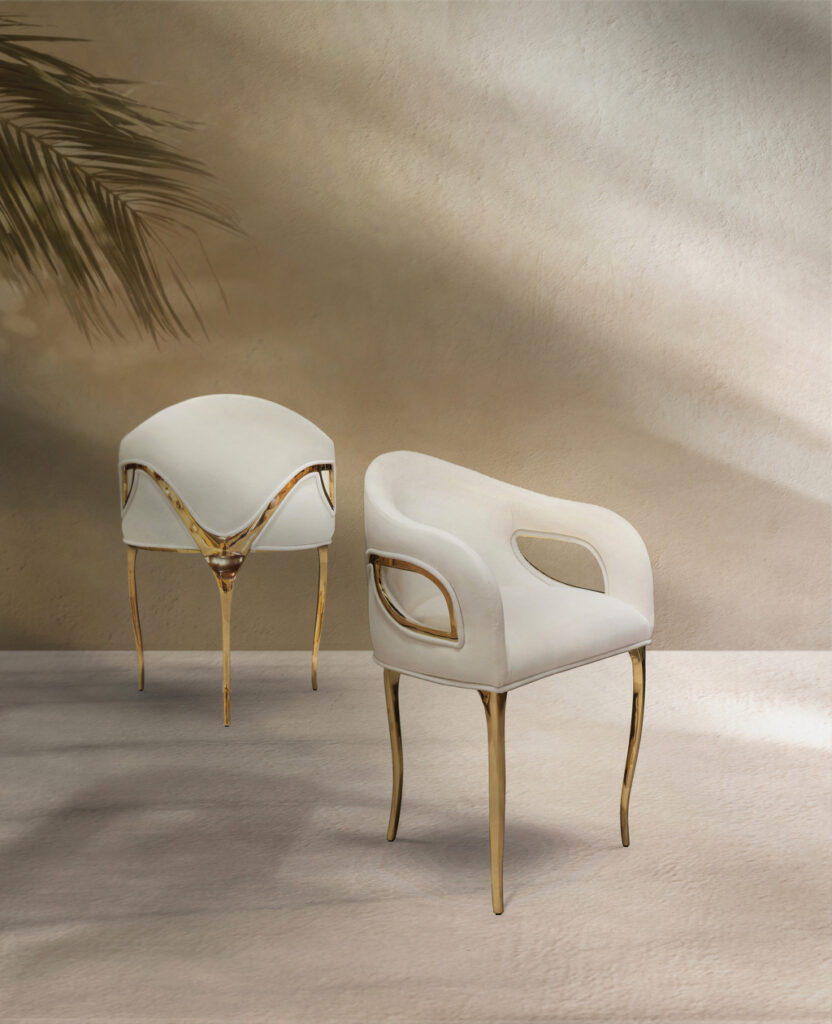 Two ivory white Chandra Chairs seen from behind in a warm, sandy setting