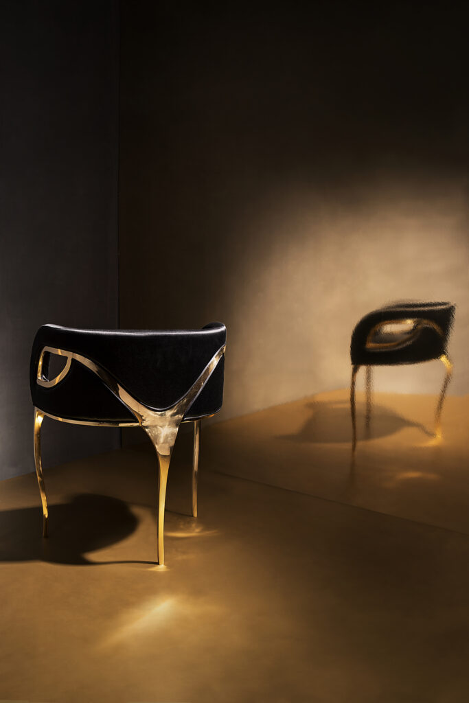 Chandra Chair in black velvet and polished brass against a dramatic dark background, two angles shown