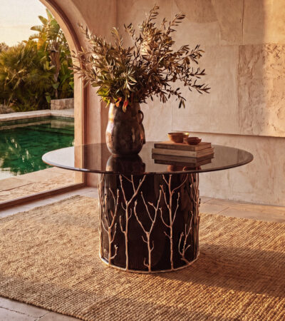 the story behind the enchanted collection by koket - enchanted branch metal handmade table in a beautiful stone foyer setting with a pool in the background